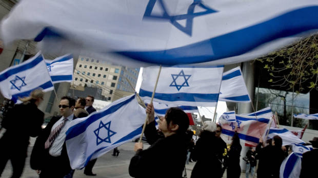 adults in outdoor area waving israeli flags
